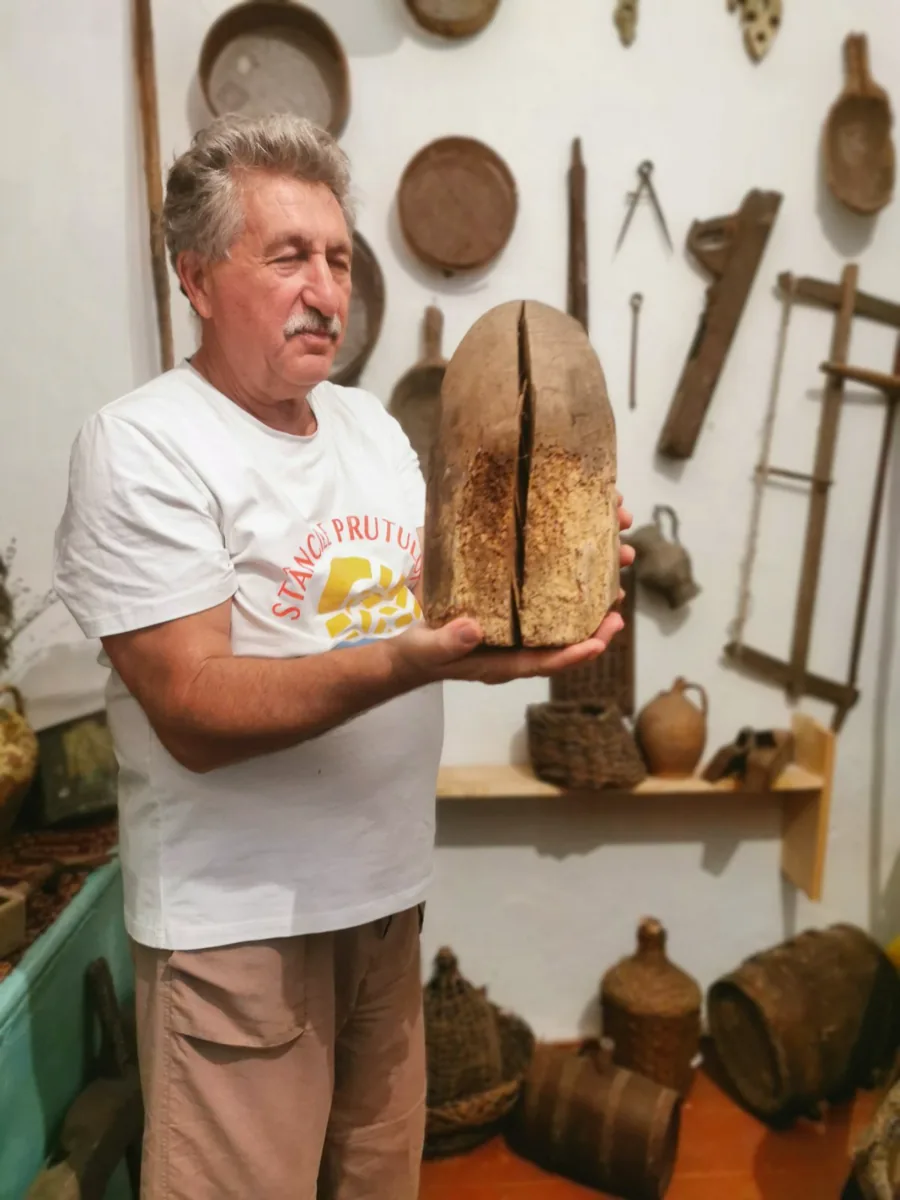 Nicolae Moscalu ținând în mână un exponat de lemn, în sala etnografică